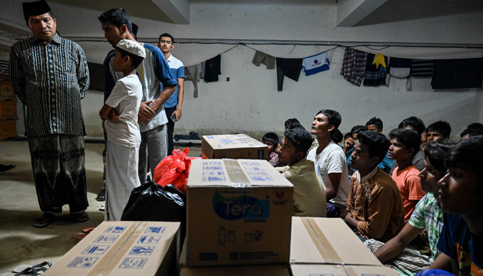 A representative (L) from the Aceh Ulema Council (MPU) donated food to Rohingya refugees at a temporary shelter in the basement of a government building in Banda Aceh on December 30, 2023. —