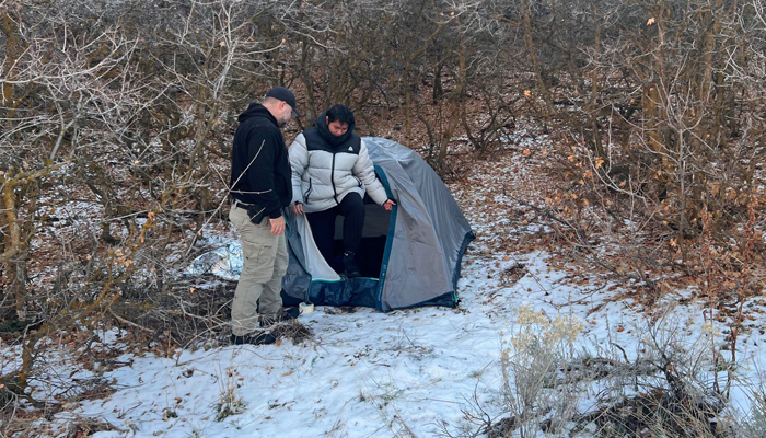 This photo on January 1, 2024 shows a police officer standing next to Kai Zhuang at the site where he was found in the mountains near Brigham City, Utah, on December 31, 2023, after being reported missing. — AFP