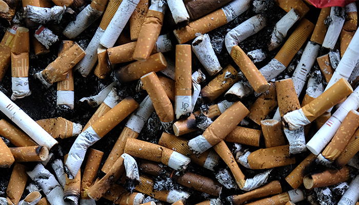 An ashtray filled with cigarettes butts is seen on an outdoor smoking stand at a bus stop.—AFP