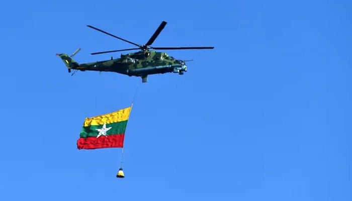 A Myanmar military helicopter carries the national flag over a parade ground to mark the countrys Independence Day in Naypyidaw on January 4, 2023. — AFP