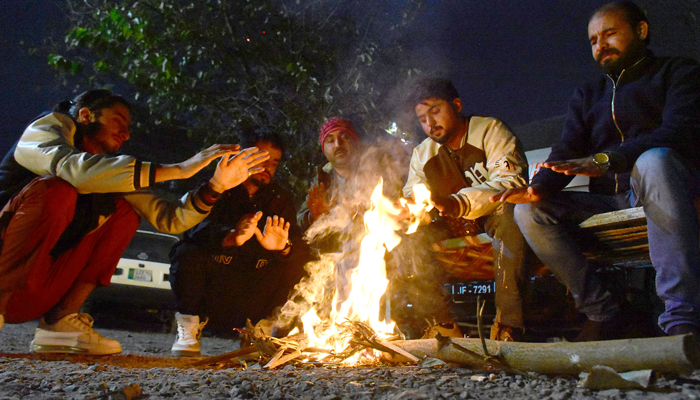 Vendors sit around the fire along the roadside to counter coldness during the extreme weather conditions of winter in the Federal Capital on January 8, 2024.— Online