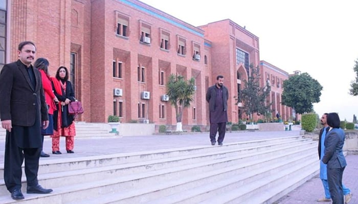 People take a pose outside the International Islamic University (IIU) Islamabad building on  December 8, 2023. — Facebook/International Islamic University, Islamabad (IIUI)