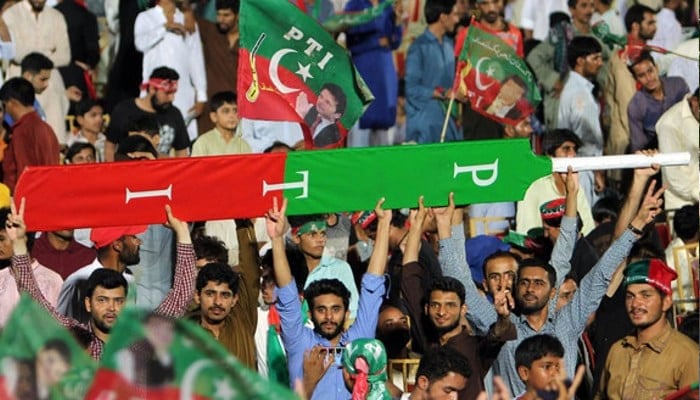 Supporters of former prime minister Imran Khan hold a giant cricket bat with the colours and initials of the party. — AFP/File