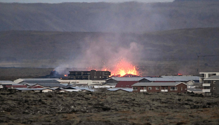 Lava explosions and billowing smoke are seen near residential buildings in the southwestern Icelandic town of Grindavik after a volcanic eruption on January 14, 2024. — AFP