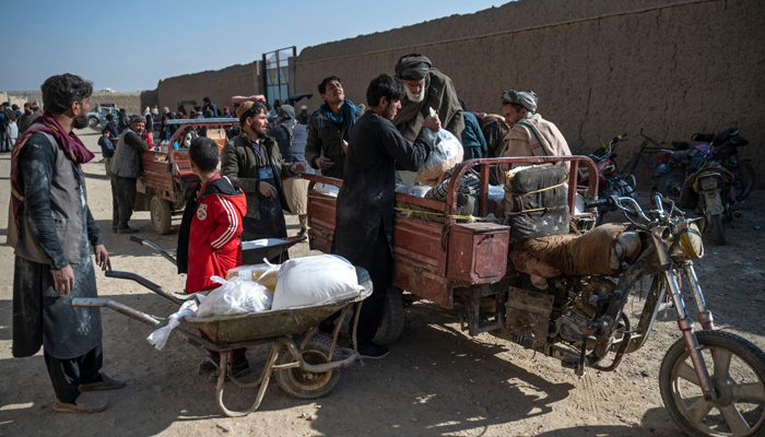 Afghan men load food packets on a vehicle distributed as humanitarian aid by the UN World Food Programme at Nawabad Kako Sahib area in Baraki Barak district of Logar Province on January 7, 2024. — AFP