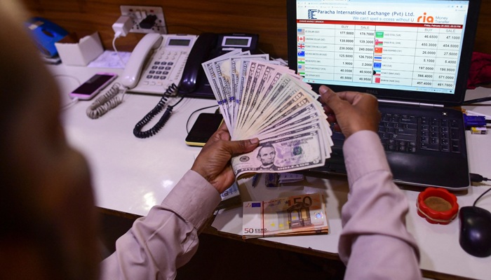 A foreign currency dealer counts US dollar bills at a shop in Karachi on February 25, 2022. — AFP