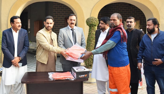 In this image, Commissioner Rawalpindi Division Liaqat Ali Chatha (C) and CEO Rawalpindi Waste Management Company (RWMC) Rana Sajid Safdar (2nd L) distributing warm uniforms, jackets, and shoes among the workers of RWMC at the commissioner’s office on January 25, 2024. — Facebook/Commissioner Rawalpindi Official