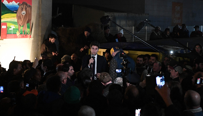 French PM Gabriel Attal (C) addresses farmers blockading the A64 autoroute (motorway) in protest against taxation and declining income, near Carbonne, south of Toulouse, on January 26, 2024. — AFP