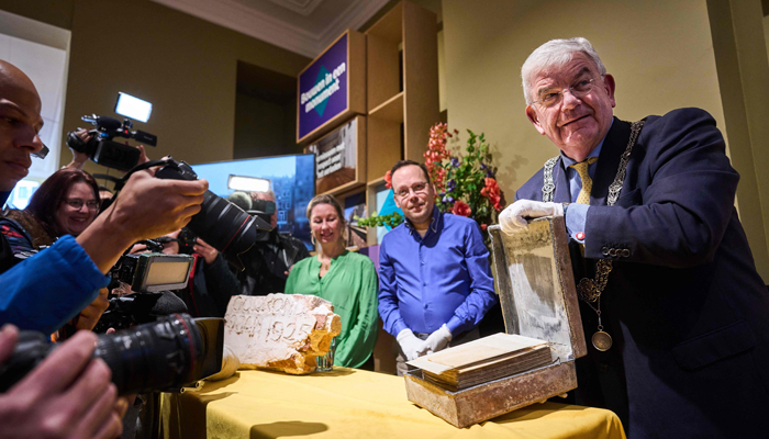 The Hague mayor Jan van Zanen (R) opens a time capsule found under the pedestal of the equestrian statue of King William II in The Hague, on January 29, 2024. — AFP