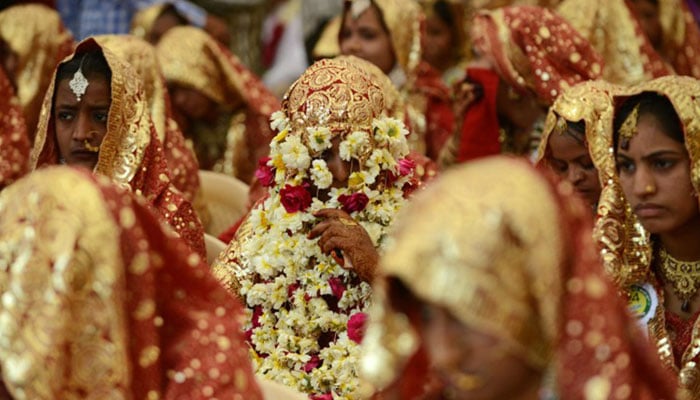 This picture shows an Indian bride has her face covered with flower garlands during a mass wedding ceremony in Ahmedabad, India. — AFP/File