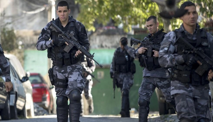 Militarized police officers carrying assault rifles patrol a street of the Mangueira shanty town in Rio de Janeiro, Brazil on July 17, 2017. — AFP