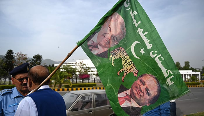 A supporter of PML-N holds a party flag with images of Shehbaz Sharif and his elder brother and three-time prime minister Nawaz Sharif outside the Parliament House in Islamabad on April 11, 2022. — AFP