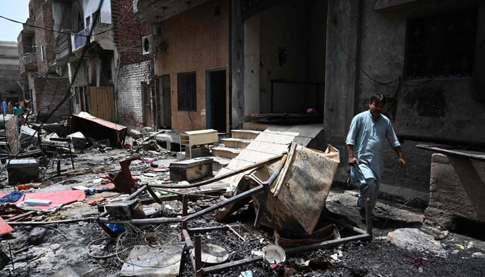 A man walks amid debris of houses torched along a street near Saint John Church in Jaranwala on the outskirts of Faisalabad on August 17, 2023, a day after an attack over blasphemy allegations. — AFP