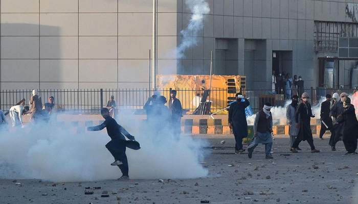 A Pakistan Tehreek-e-Insaf (PTI) party activist and supporter of Imran Khan throws back a tear gas shell towards police during a protest on May 9, 2023. — AFP