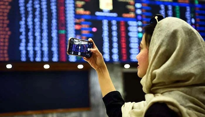 A woman takes pictures of the electronic board displaying data at the Pakistan Stock Exchange in Karachi on December 21, 2022. — PPI