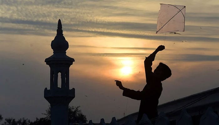 A Pakistani boy flies a kite on the roof of a mosque during sunset in Pakistan. — AFP/File