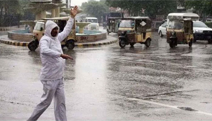 Image showing a traffic warden giving directions to cars amid rain on the streets of Karachi. — Screengrab/Geo News/ file