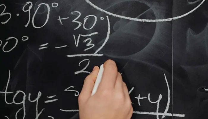 This representational image shows a person solving a maths problem. — Pexels