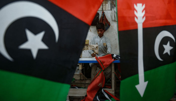 A worker stitches flags of PPP at a factory in Karachi on January 15, 2024. — AFP
