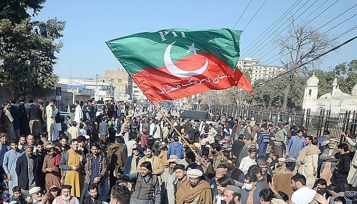 In this image, a PTI worker holding a Flag of the party. — INP/File