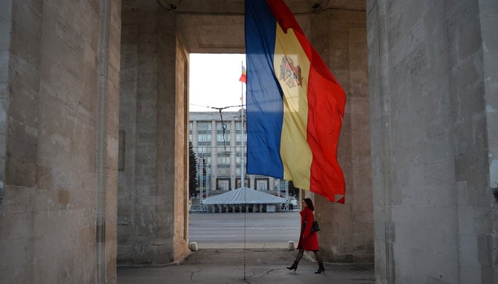 A woman walks under the Triumphal Arch next to the Moldovan flag in Chisinau. — AFP/File