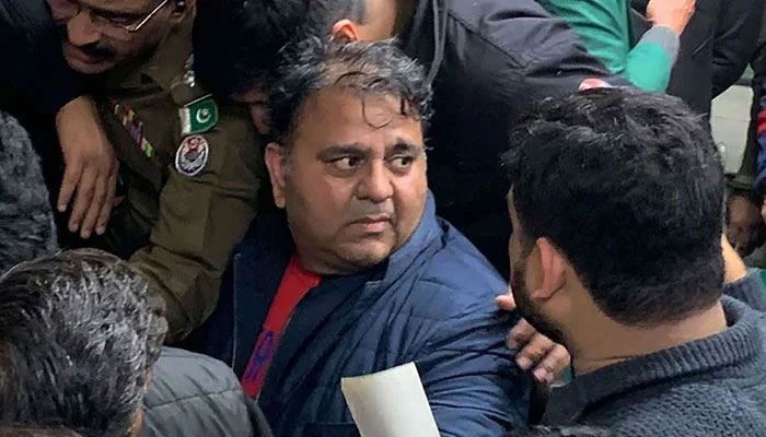 Police officials escort former federal minister Fawad Chaudhry to present him before a court in Lahore. — AFP/File