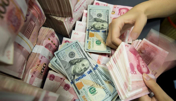 A Chinese bank employee counts 100-yuan notes and U.S. dollar bills at a bank counter in Nantong, China, on August 28, 2019. — AFP