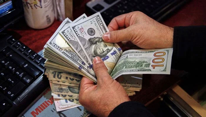 A currency exchange dealer counting $100 bills. — AFP/File