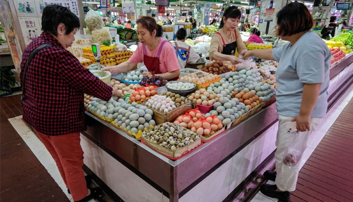 Customers select eggs at a market in Wuhan, in central China’s Hubei province on April 16, 2024. – AFP