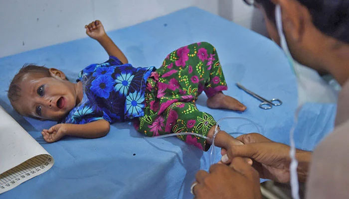 A medic treats a baby girl at a hospital. — AFP/File