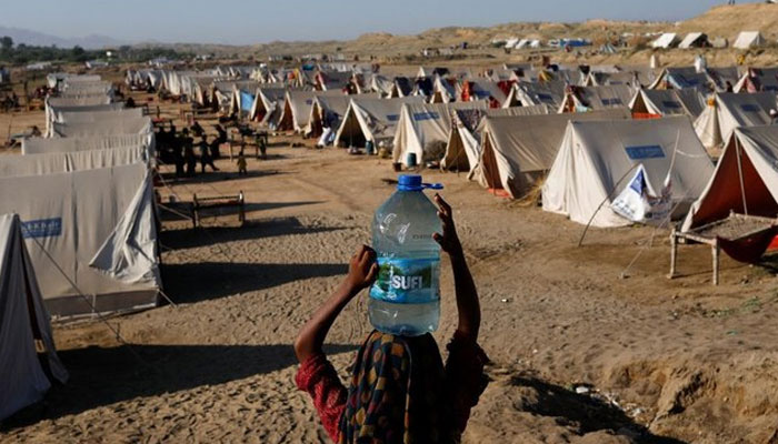 A displaced girl carries a bottle of water she filled from nearby stranded flood-waters, as her family takes refuge in a camp, in Sehwan, Pakistan, September 30, 2022. — Reuters