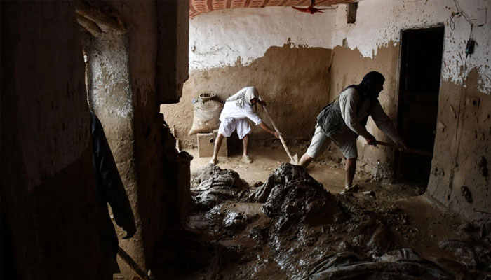 Afghan men shovel mud from a house following flash floods after heavy rainfall in Baghlan province. — AFP/File