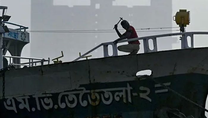 A dockyard worker hammers a ship at a dockyard on the banks of the Buriganga River in Dhaka on January 9, 2024. — AFP