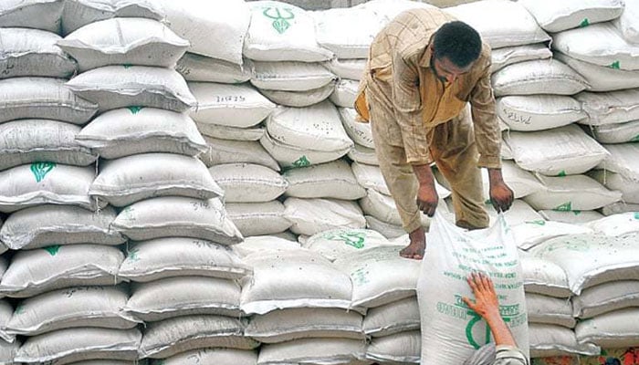 A labourer hands over a fertiliser bag to another labour. — AFP/File