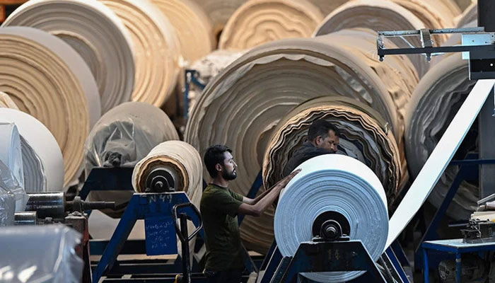 In this picture, a worker operates a machine preparing fabric at a textile mill in Lahore on July 20, 2023. — AFP