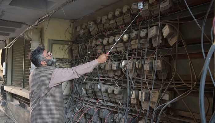 a Pakistani employee of the state-run Islamabad Electric Supply Company (IESCO), takes a meter reading with his smartphone at a commercial building in Islamabad.  — AFP/File