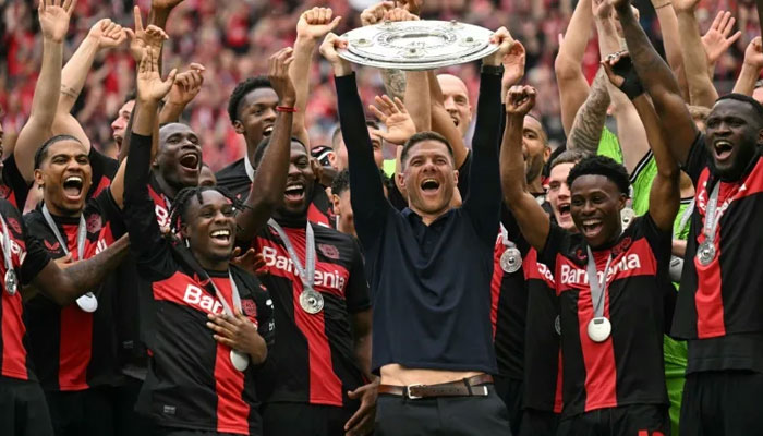 Bayer Leverkusen coach Xabi Alonso and his players celebrate with the Bundesliga trophy. — INA FASSBENDER/File