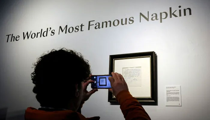 The representational image showing a person taking a photograph of the napkin on which Barcelona promised to sign Lionel Messi when he was a 13-year-old. —  Reuters/File