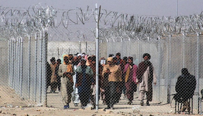 People walk along a fenced corridor as they enter Pakistan through the Pakistan-Afghanistan border. — AFP/File