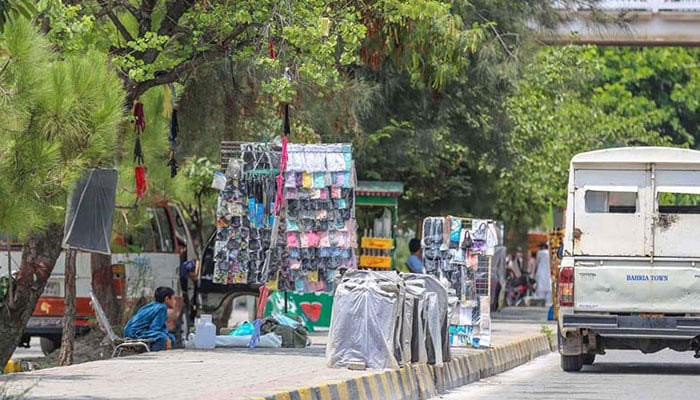 This image shows street vendors selling various items on a footpath. — APP/File
