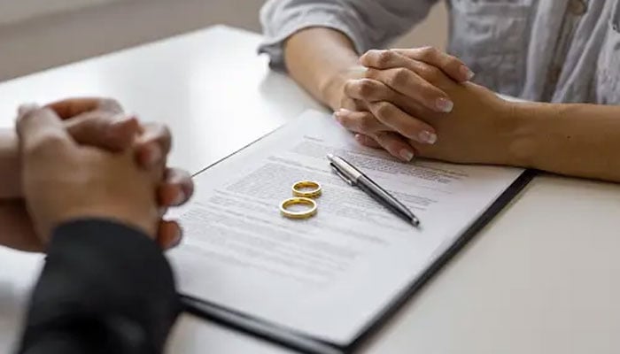 This representational image shows a man and a woman sitting with papers. — Unsplash/File