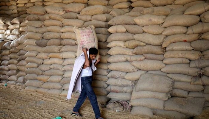 A worker carries a sack of wheat for sifting at a grain. — Reuters/File