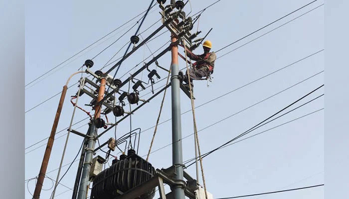 A representational image shows a person working on an electric pole. — AFP/File