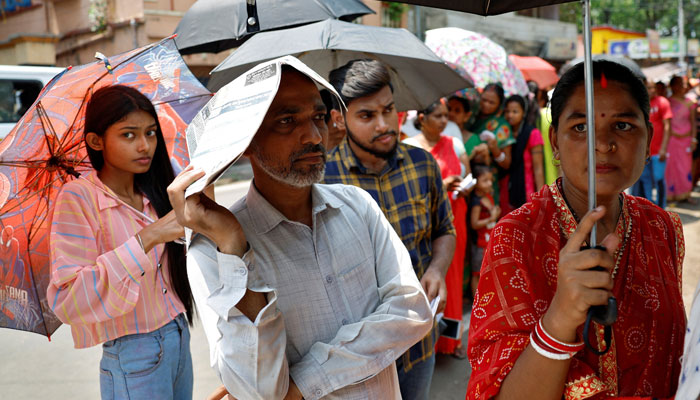 A man uses a newspaper as others use umbrellas to protect themselves from the heat as they wait to vote outside a polling station during the fifth phase of India’s general election in Howrah district of the eastern state of West Bengal, India, May 20, 2024. — Reuters