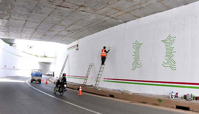 A Painter busy making different designs on the wall of underpass. — APP/File