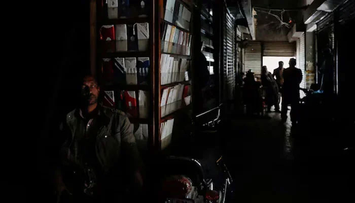 A man sits outside his shop during a power breakdown in Pakistan. — Reuters/File