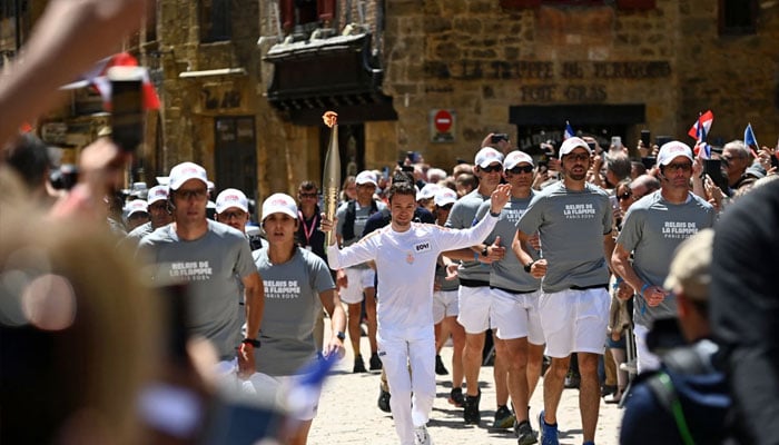 French trail runner Paul Mathou runs with the flame Wednesday during the Olympic torch relay in Sarlat-la-Canéda, southwestern France.— AFP/File