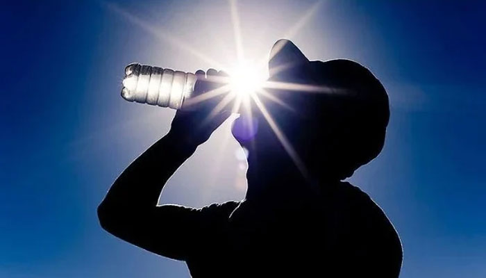 Silhouette of a man drinking water from a bottle is seen against the shining sun. — AFP/file