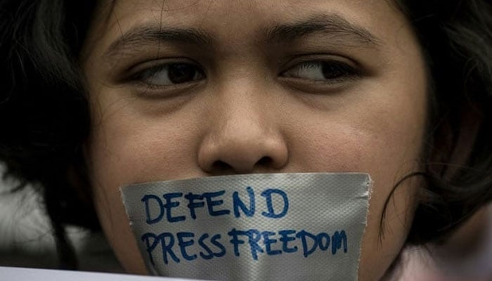 A representational image of a protester advocating for media freedom with defend press freedom written on a piece of tape. — AFP/File