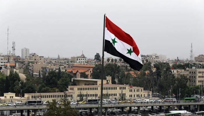 Syrian flag flies near a bus station in the Baramkeh neighbourhood of Damascus. — AFP/File